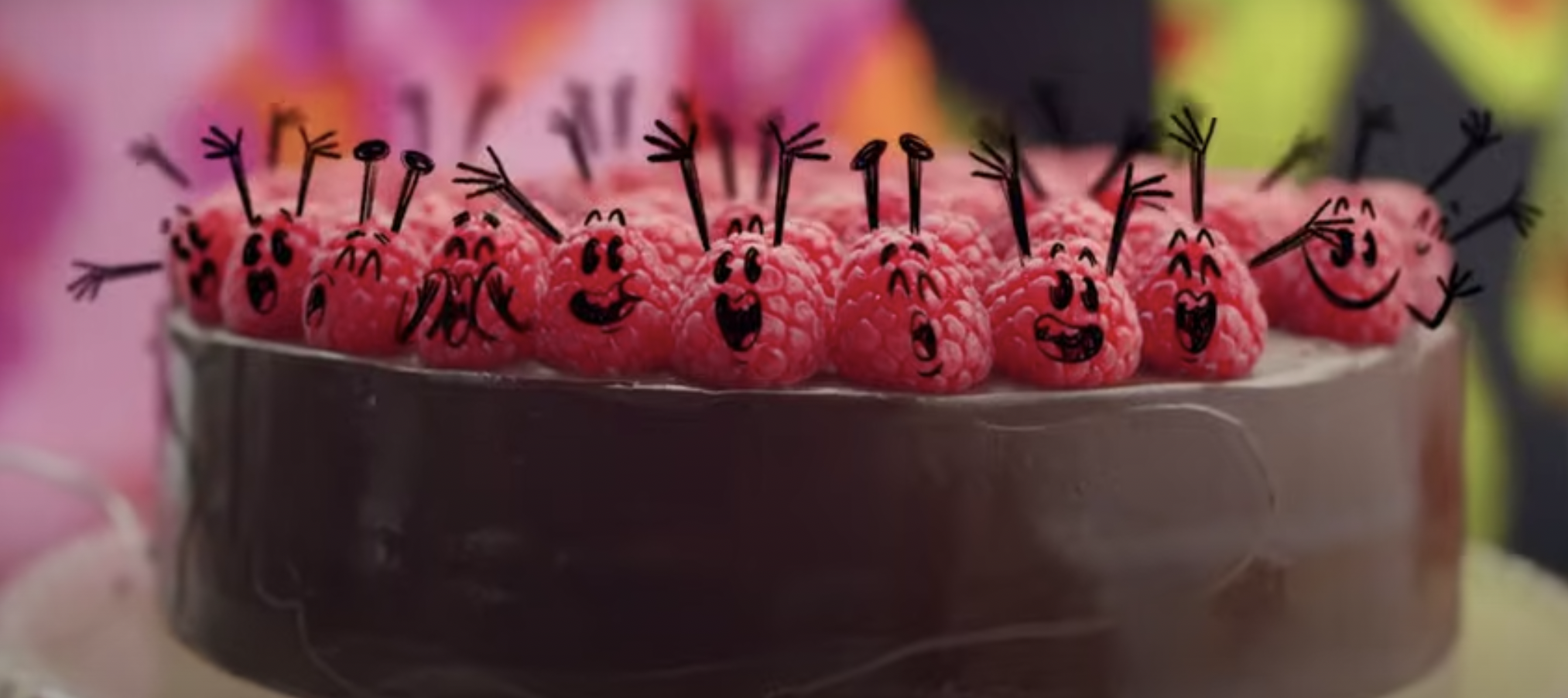 Animated raspberries cheer atop a chocolate ganache cake.