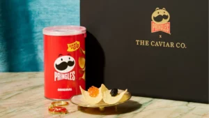 A small can of Pringles beside a branded Caviar Co. box and a chip with caviar on it