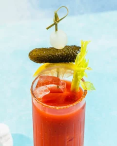 A Bloody Mary cocktail in a tall glass garnished with a pickle, onion, celery