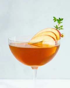 An apple cider and bourbon in a wine glass garnished with apple slices