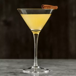 A Modern English cocktail in a martini glass with a cinnamon stick garnish