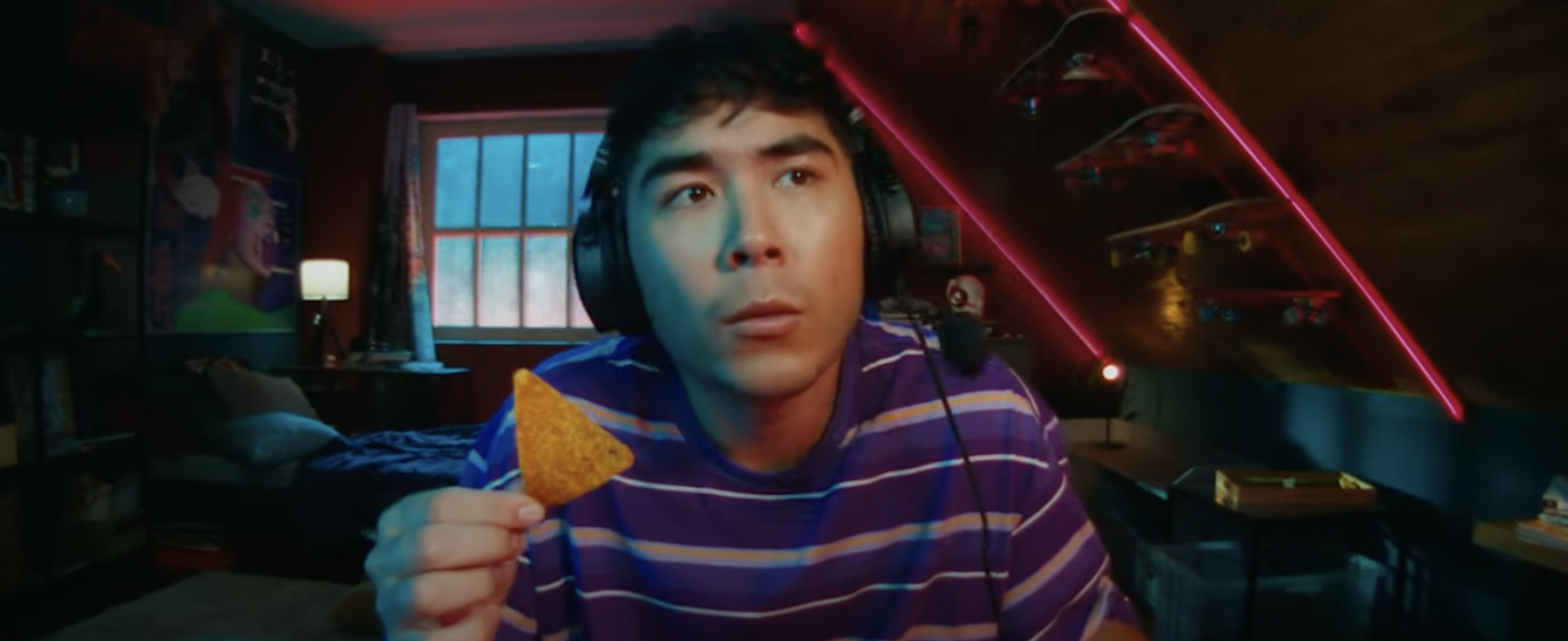A gamer wears headphones and holds a Dorito
