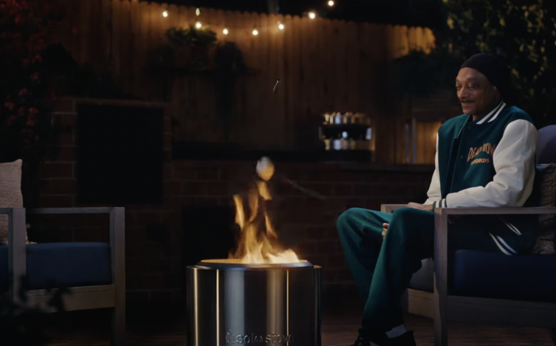 Snoop Dogg roasts a marshmallow outside over a Solo Stove smokeless firepit.