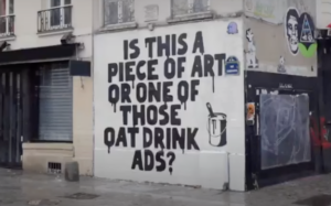 "Is this a piece of art or one of those oat drink ads" is spray painted on a building