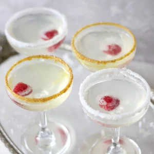Four prosecco martinis garnished with raspberry and sugar rims