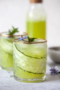 Two glasses of cucumber lime mocktail garnished with cucumber ribbons and mint