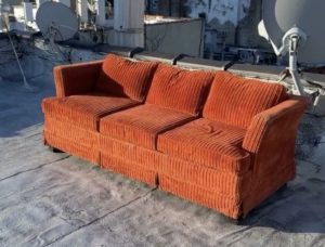 An old red corduroy couch on rooftop in NYC