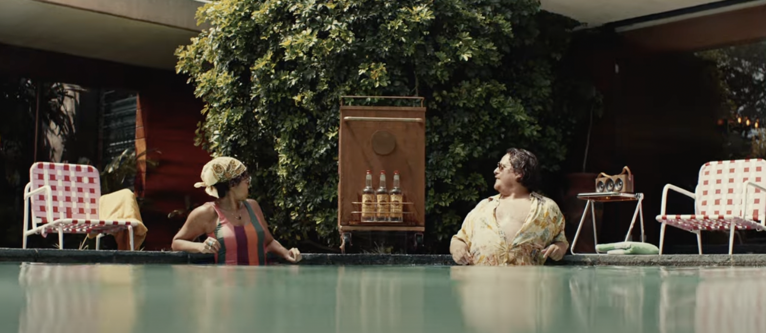 A Tito's bar cart floats between two people in a cabana pool