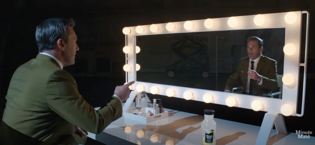 Jon Hamm points to his own reflection in a lighted mirror