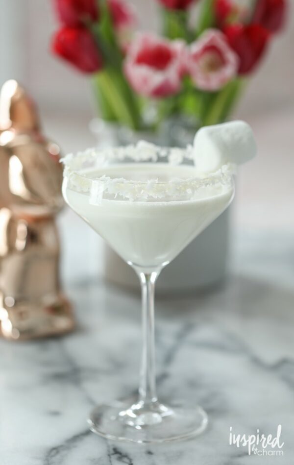 A white martini in a martini glass garnished with coconut and marshmallow