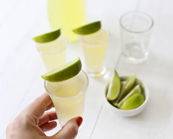 Green tea shots in shot glasses with lime wedges